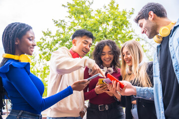 A group of young multi-ethnic teenage friends using cell phones in the city campus. Technology addicted millennial community concept. Social Media communication generation Z
