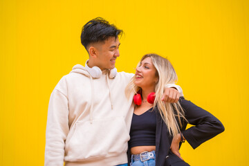 Obraz premium Portrait of a multi-ethnic couple of Asian man and Caucasian woman on a yellow background, knowing looks