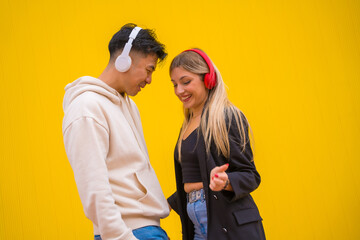 Multiethnic couple of Asian man and Caucasian woman on a yellow background, dancing bachata and salsa