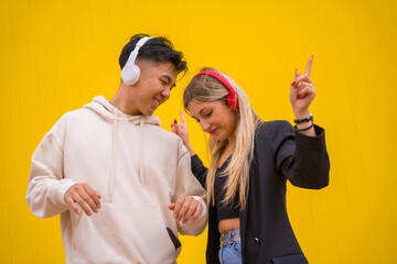 Multiethnic couple of Asian man and Caucasian woman on a yellow background, dancing bachata and salsa
