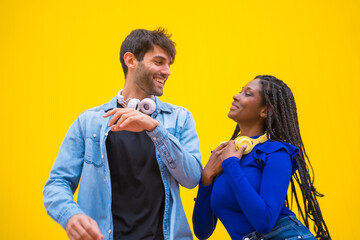 Obraz premium Multiethnic wedding couple of Caucasian man and woman of black ethnicity on a yellow background having fun, dancing salsa and latin music