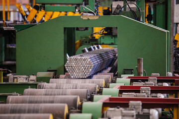 Packs of rolled metal bars on roller conveyor