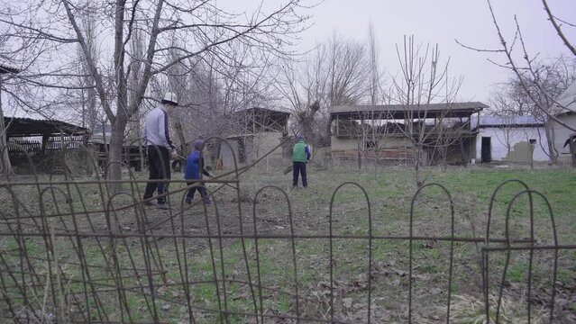 The times of the Soviet Union. A man teaches his sons to work. They clean the garden with a rake