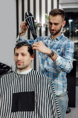 Professional hairdresser working with client in barbershop