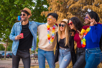 Group portrait of multi ethnic friends having a party in a park - Diverse young people with glasses...