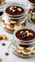 Cashew and dates vegan tiramisu with chocolate in portion jars. Healthy lifestyle no bake dessert close up - generative ai