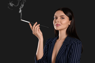 Woman using long cigarette holder for smoking on black background