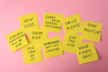 Paper notes with life-affirming phrases on pink background