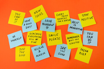 Paper notes with life-affirming phrases on orange background