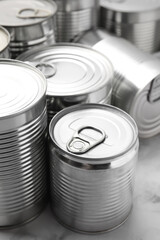 Many closed tin cans on white marble table, closeup
