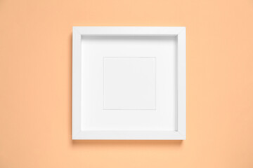 Empty photo frame on pale orange background, top view. Space for design