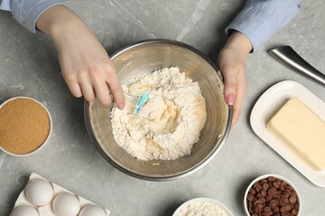 Cooking chocolate chip cookies. Woman making dough at light grey marble table, top view