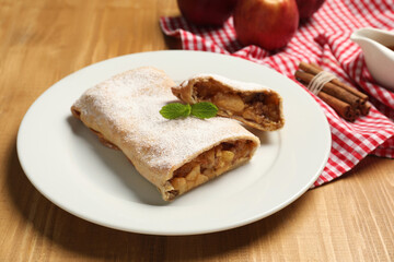 Delicious strudel with apples, nuts and raisins on wooden table, closeup