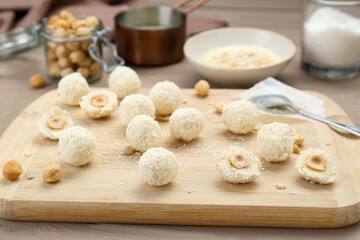 Delicious candies with coconut flakes and hazelnut on wooden table