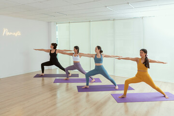 A group of women in yoga class doing the warrior pose