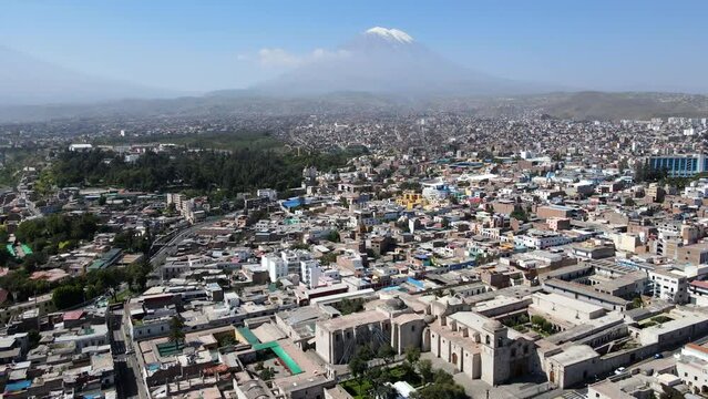 Aerial shot drone orbits to right around San Javier church with Misti Volcano in the distance