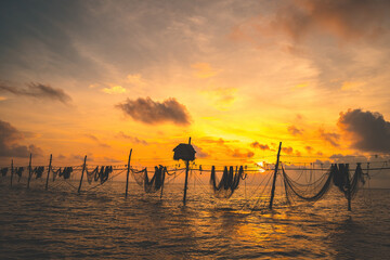 Silhouette of fishermen casting a nets on fishing poles on sunrise. Traditional fishermen prepare...