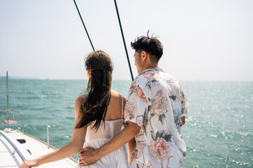 Asian young romantic couple looking at beautiful view during yachting. 