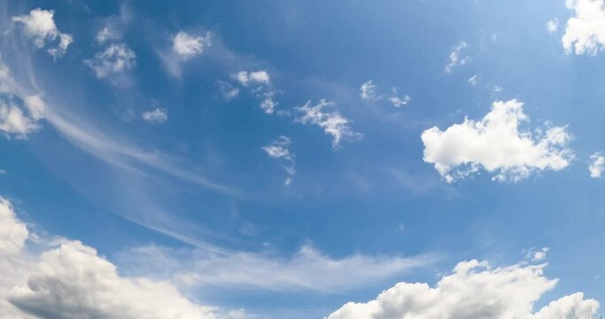 Beautiful blue summer sky with white clouds moving slowly. Soft fluffy cloudscape changing shape from low angle view.