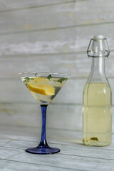 summer cocktail with lemon, mint and ice cubes in a transparent martini glass on a light background