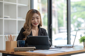 Asian Business woman using calculator and laptop for doing math finance on an office desk, tax, report, accounting, statistics, and analytical research concept