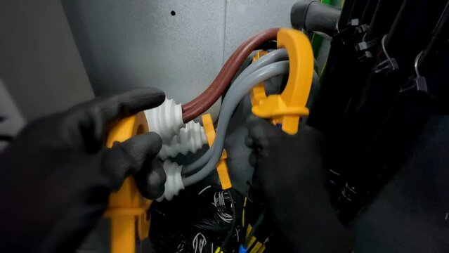 Electricians clamp ammeters to big electrical cables to measure current as part of a safety industrial idea.