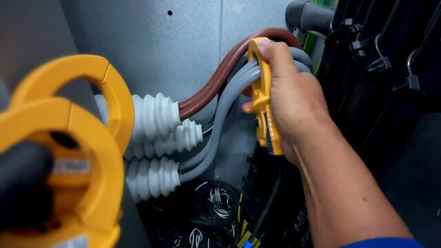 Electricians clamp ammeters to big electrical cables to measure current as part of a safety industrial idea.