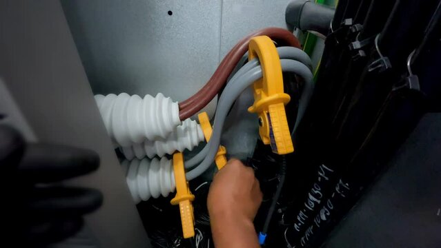 Electricians clamp ammeters to big electrical cables to measure current as part of a safety industrial idea.
