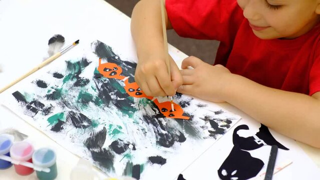 Child making abstract card for the  halloween. Funny crafts from paper. Halloween decor. The concept for Halloween. DIY. Children's art project
