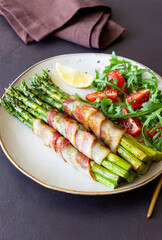 Asparagus baked with bacon and arugula and tomato salad. Healthy eating. Diet.