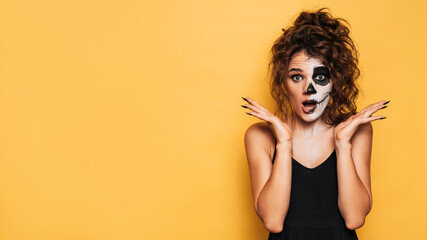 A young woman dressed in a Halloween costume with makeup for the holiday on a yellow isolated...