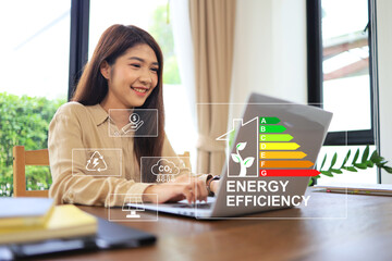 Businesswoman using computer home's energy efficiency rating label, which the energy efficiency of...