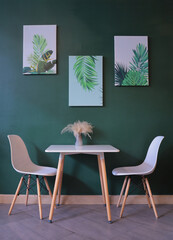white table and chairs in a coffee shop green room decorated with pictures