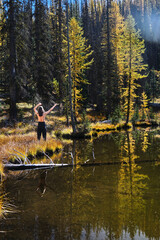 Fototapeta na wymiar Woman by serene lake with reflections of yellow trees enjoying the nature. Colorado. United States of America