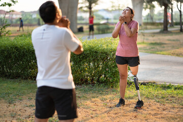 Exercise Asia woman with prosthetic leg and friend stretching at the park city