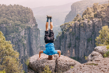 Man standing on his head on the edge of a big cliff with view of canyon Tazi in Turkey. Yoga pose...