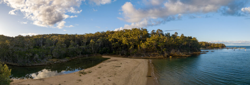 Late afternoon panorama by the sea and creek with clouds in the blue sky