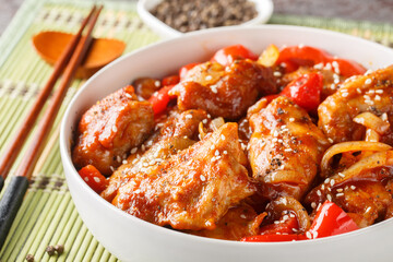 Black Pepper chicken, is a fast, easy stir-fry made with chicken, onions, and peppers seasoned with oyster sauce and loads of black pepper closeup on the bowl on the table. Horizontal