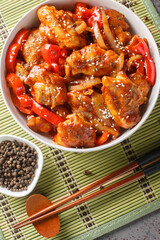 Black pepper chicken with juicy tender fillet, crisp vegetables and a rich savory black pepper sauce closeup on the bowl on the table. Vertical top view from above