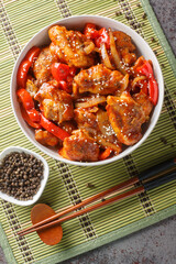 Chinese black pepper chicken with vegetables close-up in a plate on the table. Vertical top view from above