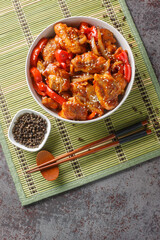 Stir-fried black pepper chicken with vegetables in a spicy sauce close-up in a plate on the table. Vertical top view from above