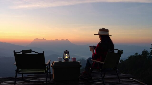 Female tourist sits on a camping chair and takes pictures of mountain scenery and sunrise sky.Chiang Mai Thailand
