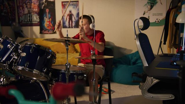 Young boy plays on drum kit at home. Elderly man irritated by noisy neighbor, screams, knocks on wall. Low level of sound insulation. Apartments separated by wall. Neighbourhood concept. Dolly shot.