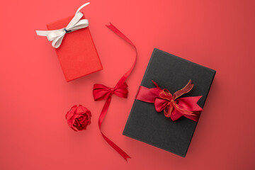 Red rose and black gift with red ribbon on red background