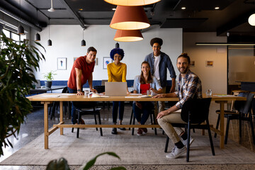 Portrait of diverse male and female colleagues using laptop and tablet in casual office meeting