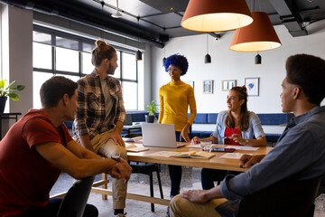 Happy diverse male and female colleagues using laptop and tablet in casual office meeting