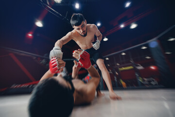 Two man MMA boxers fighters in fights without rules in ring octagon, dark background, motion blur