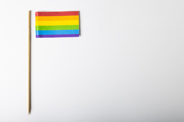 Overhead view of rainbow flag with stick isolated on white background, copy space