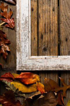 Overhead view of autumn leaves and empty old picture frame over wooden table