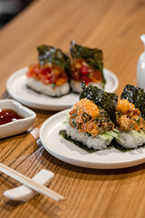 Japanese opened hand sushi rolls with different fish and sauce on table